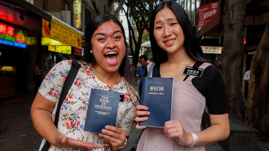 Mormon missionaries Sister Wolfgram and Sister Lu holding The Book of Mormon.