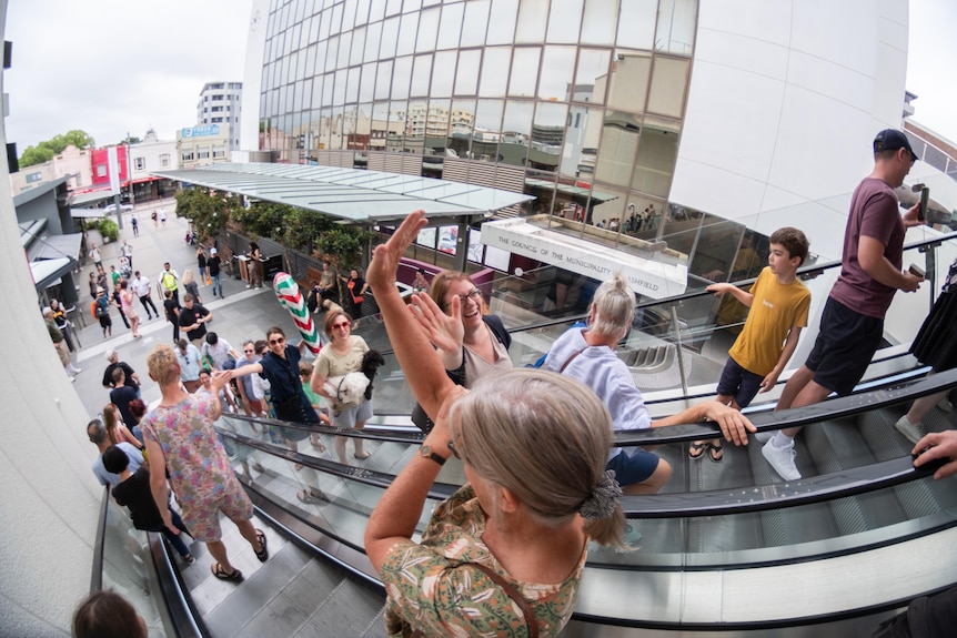 A group of people going up and down an escalator cheer