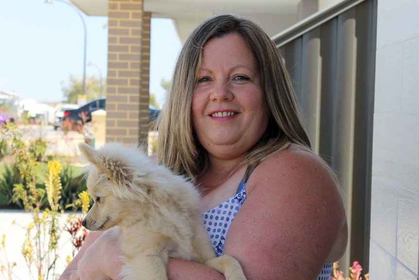 Lisa Casey cuddles her dog at the front of her Allara home.