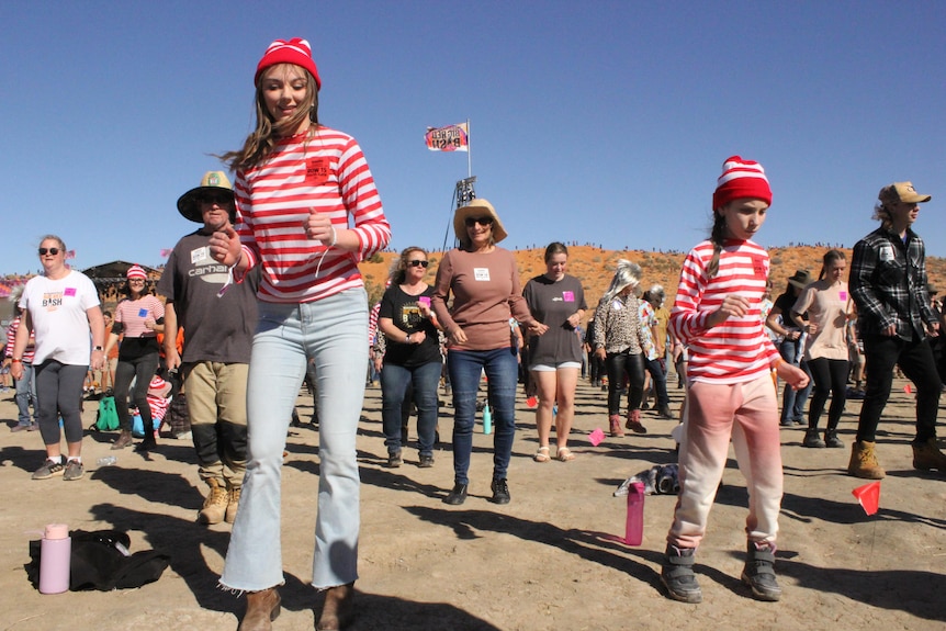 Two young women dressed in red and white stripes like 'Where's Wally' dance the nutbush.