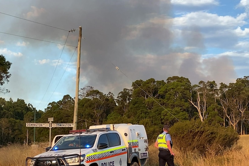 A police roadblock with smoke in the distance