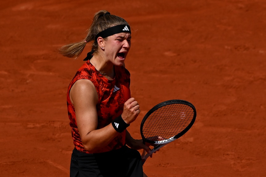 A woman screams in joy on a tennis court