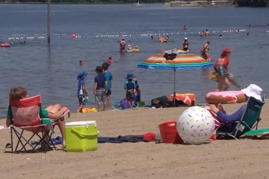 People sit on chairs and play in the water at a beach.