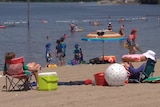 People sit on chairs and play in the water at a beach.