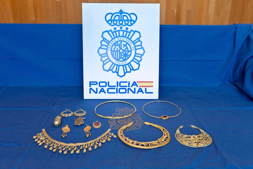 gold necklaces lay on table covered with blue velvet 