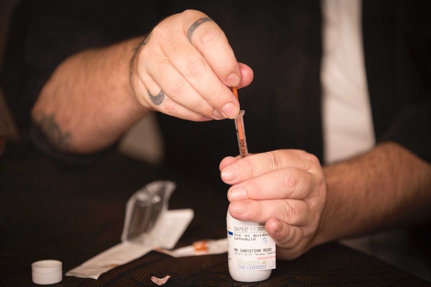 Close-up shot of hands drawing cannabis oil up into a syringe.