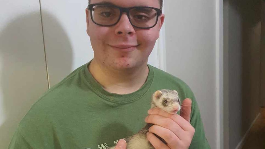 Close up shot of a teenage boy holding a ferret.