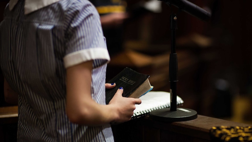 A female student places her hand on the Holy Bible in the court room drama