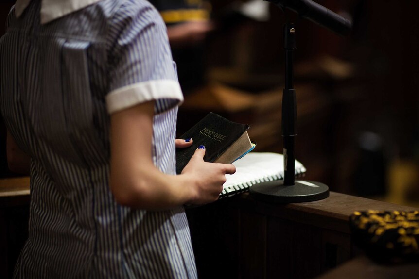 A female student places her hand on the Holy Bible in the court room drama