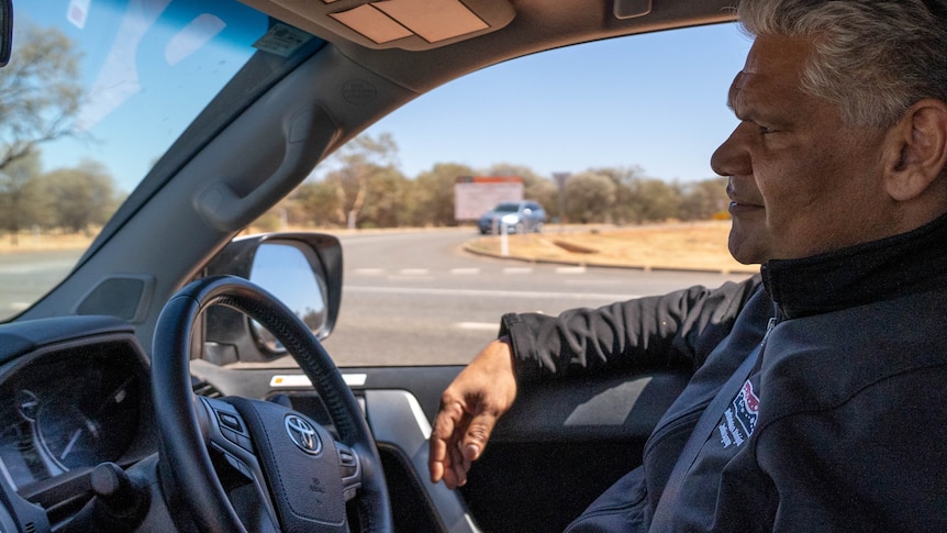 A man with silver hair driving in Alice Springs