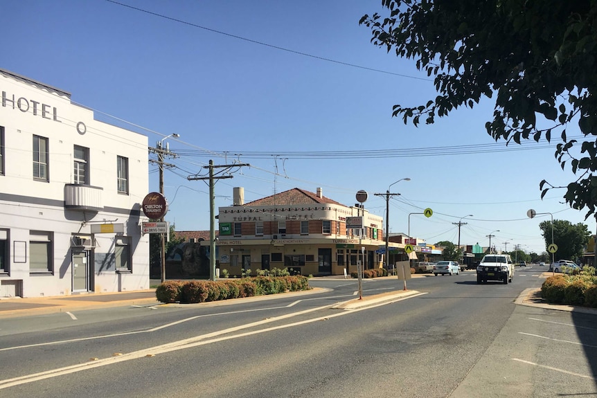 A wide road in a country town with two old-fashioned hotels.