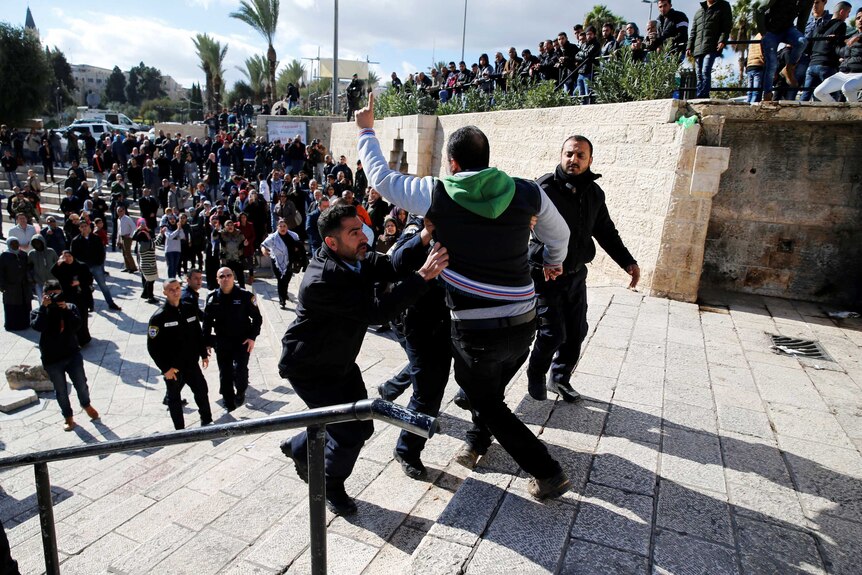 Israeli policemen scuffle with a Palestinian man during a protest