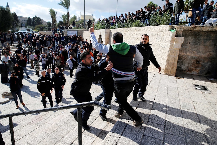 Israeli policemen scuffle with a Palestinian man during a protest