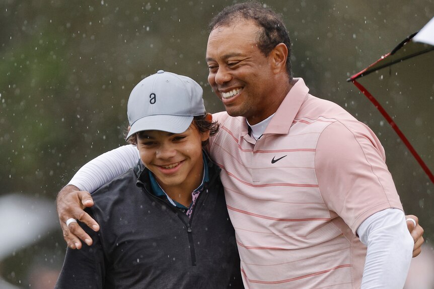Tiger Woods with his arm around the shoulder of his son Charlie at a tournament.