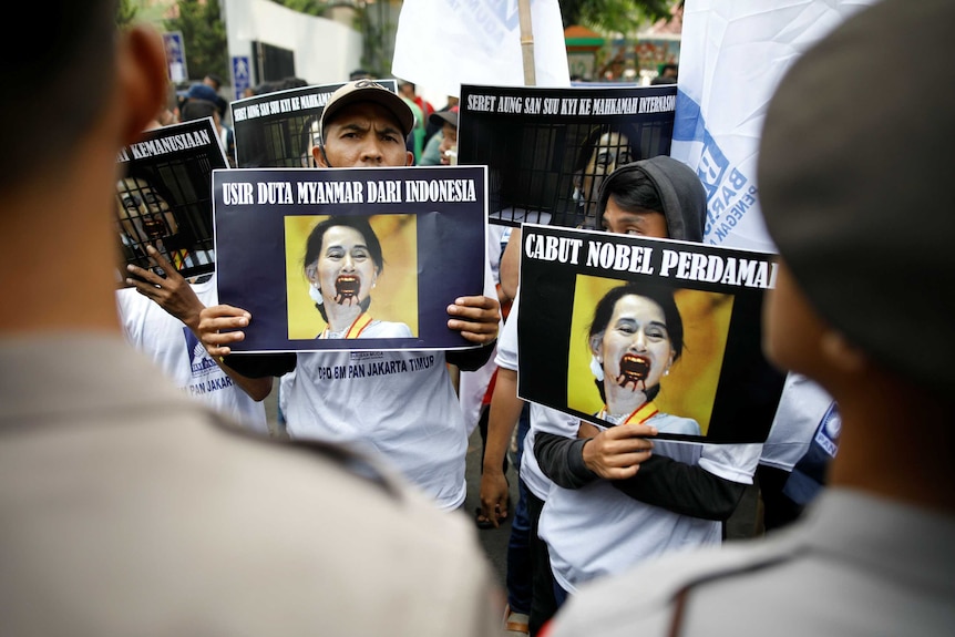 People hold up a picture of a woman bleeding from the mouth