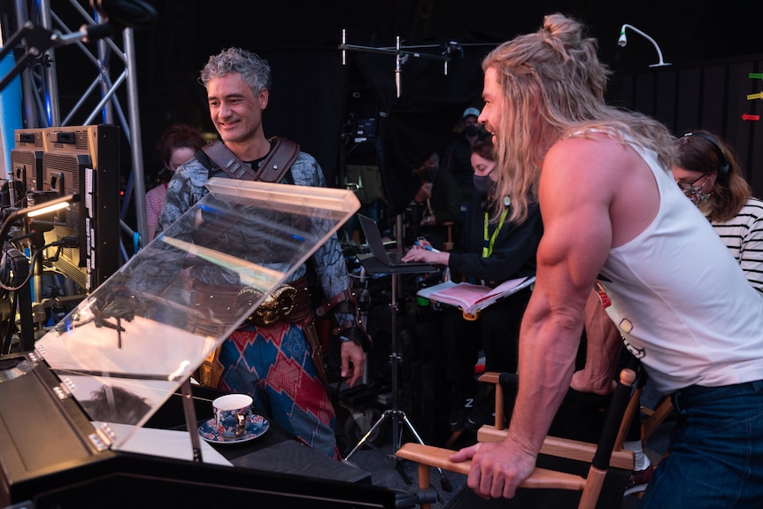 Chris Hemsworth and Taika Waititi on set of Thor with crew behind them