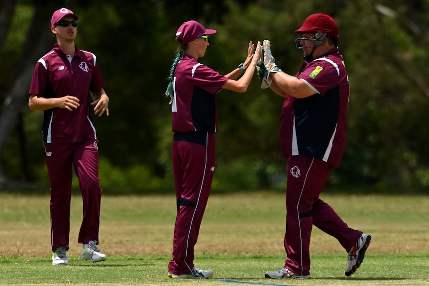 Two members of team Queensland high five on the pitch.