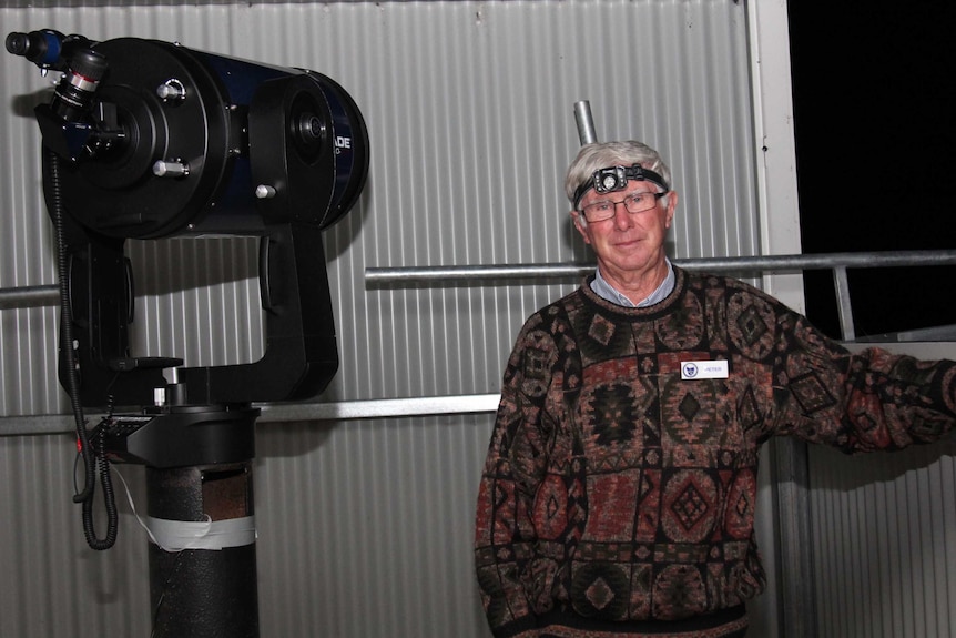 Man standing nest to a telescope