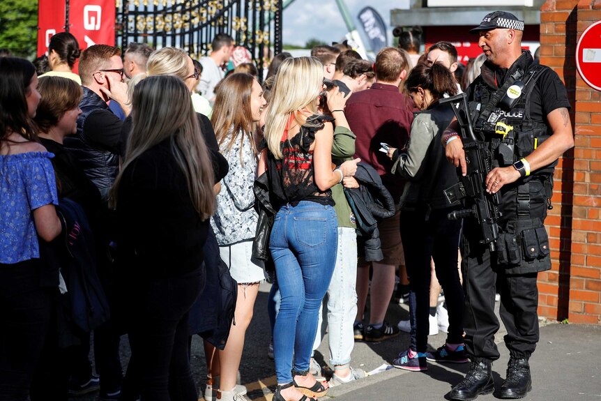Concert-goers at One Love Manchester chat with an armed police officer as they wait in line.