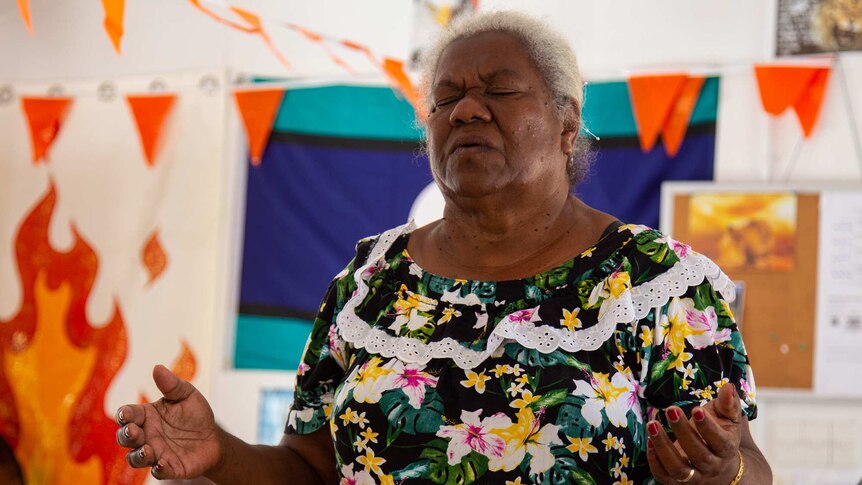 A woman with her eyes closed, praying in a church.