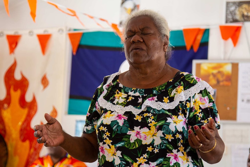 A woman with her eyes closed, praying in a church.