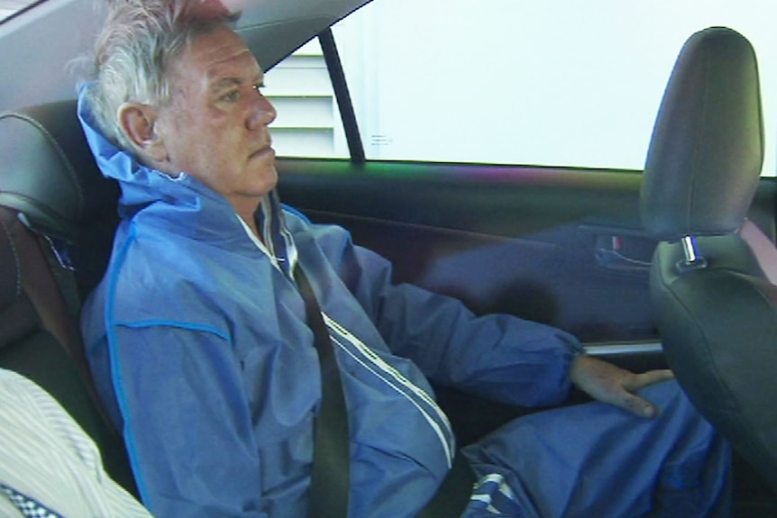 Andrew Cobby sits in the back of a police car.