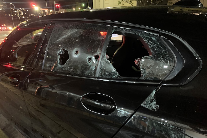a black car with shots in its window and side of the car