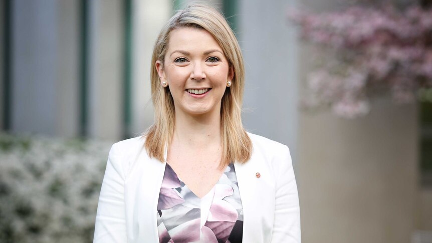 Skye Kakoschke-Moore stands in one of Parliament House's courtyards, wearing a white blazer and looking straight at the camera.