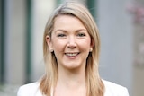 Skye Kakoschke-Moore stands in one of Parliament House's courtyards, wearing a white blazer and looking straight at the camera.