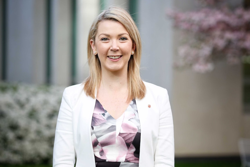 Skye Kakoschke-Moore stands in one of Parliament House's courtyards, wearing a white blazer and looking straight at the camera.