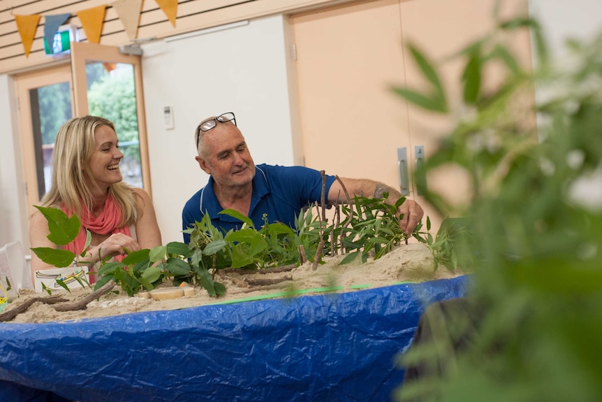 Using sand, foliage and other items, two staff from Settlers Farm School create a model of a green space on a table top