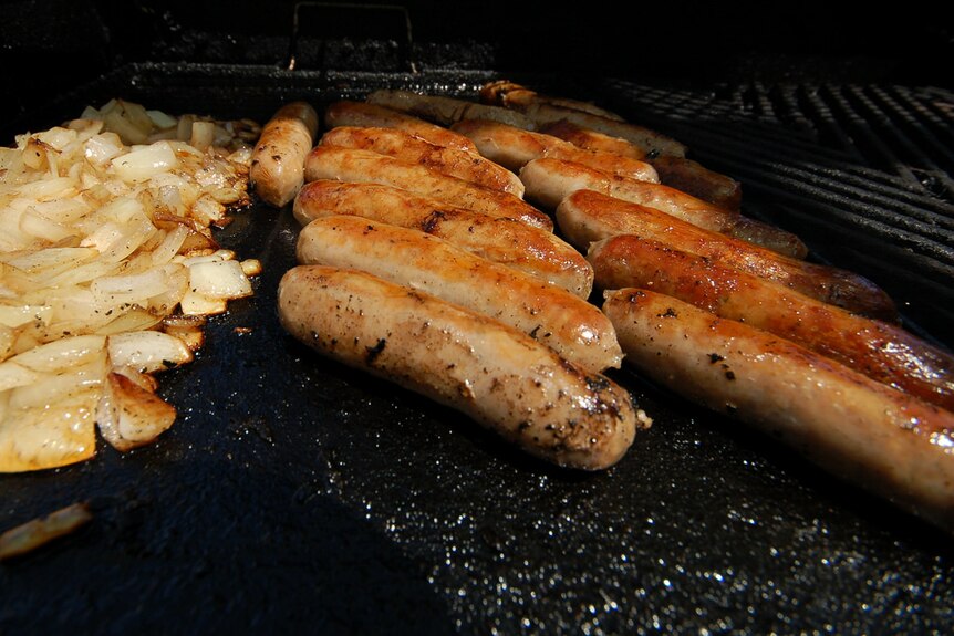 Close up of sausages and onions on a barbecue