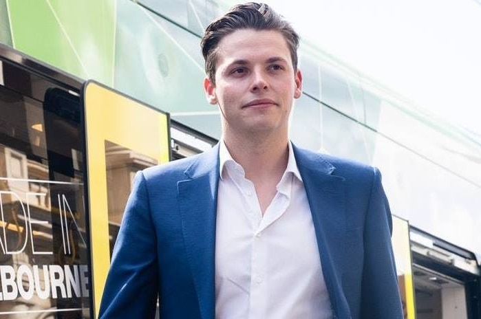 A young man stands in front of a bus that says MADE IN MELBOURNE