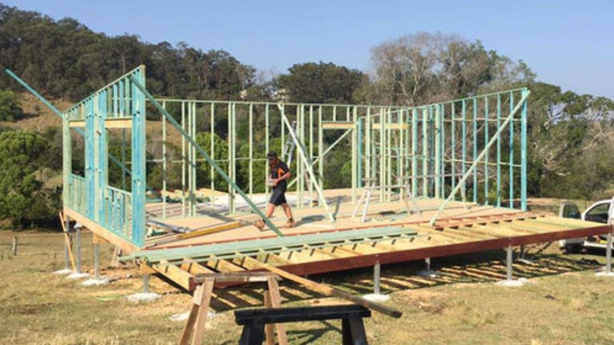 A builder walks through the frame of a home under construction.