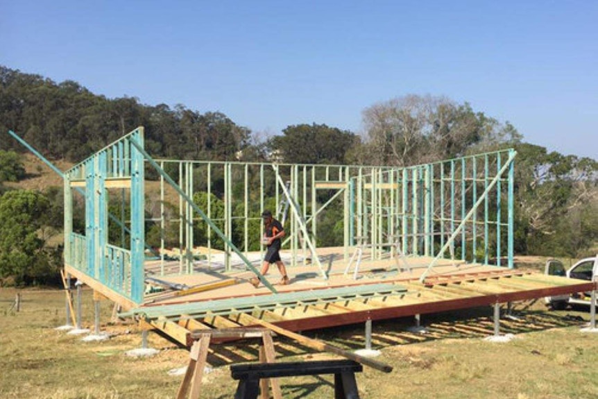 A builder walks through the frame of a home under construction.