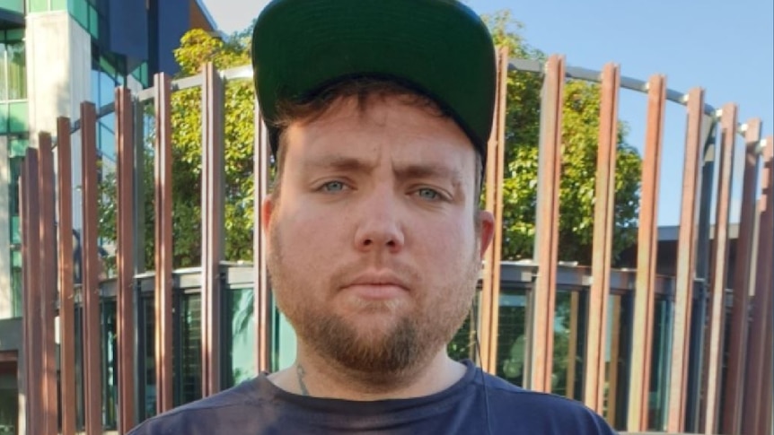 A man wearing a blue jumper and a baseball cap