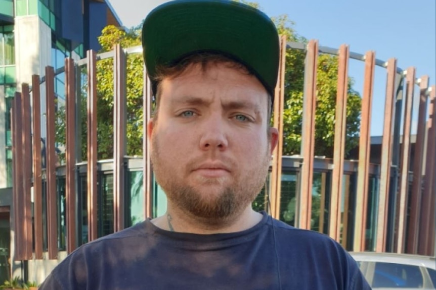 A man wearing a blue T-shirt and a baseball cap