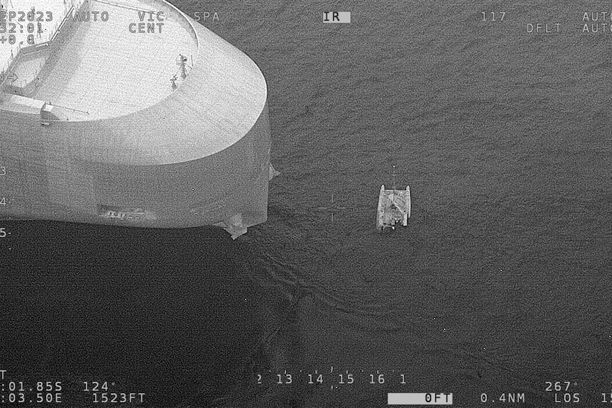 a half submerged catamaran next to a large ship