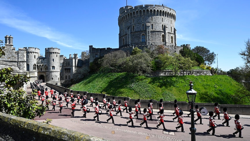 On a clear day, you view Grenadier Guards march in two rows down a path in front of Windsor Castle's round tower.