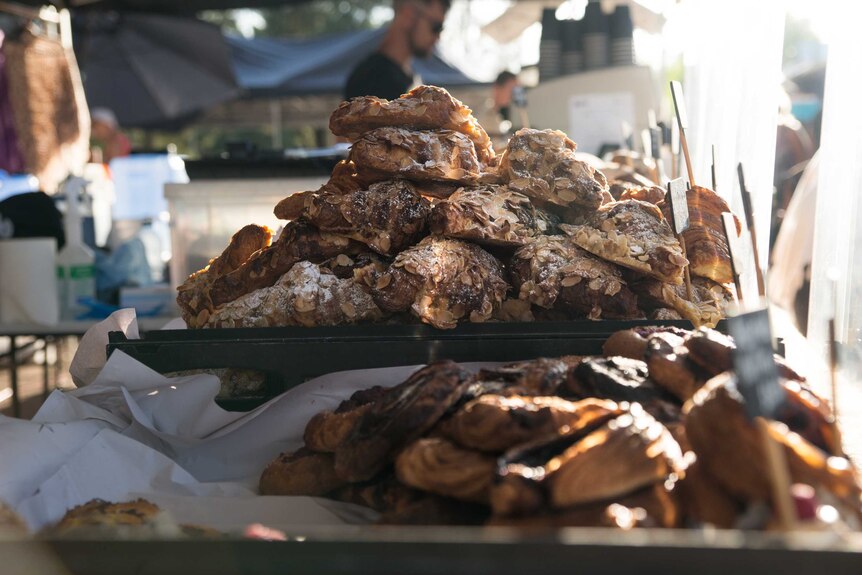 A stack of almond croissants and pastries at a market stall.