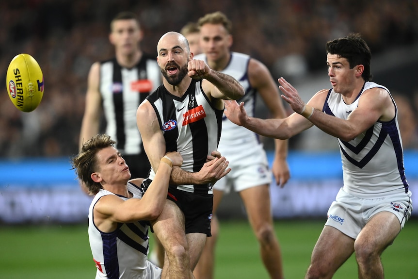 Steele Sidebottom gets a handball away while being tackled by Caleb Serong