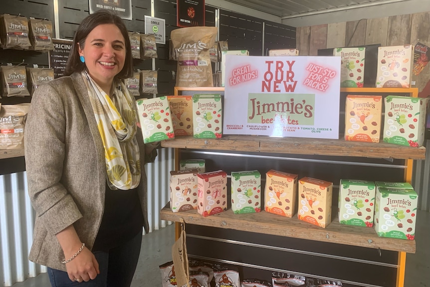 A woman standing in front of a display of packaged foods, holding one of the boxes