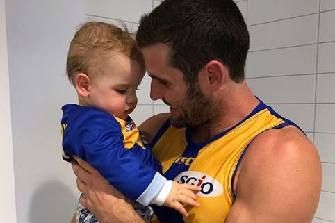 Jack Darling cuddles his young son Max, who is wearing a West Coast Eagles jumper.