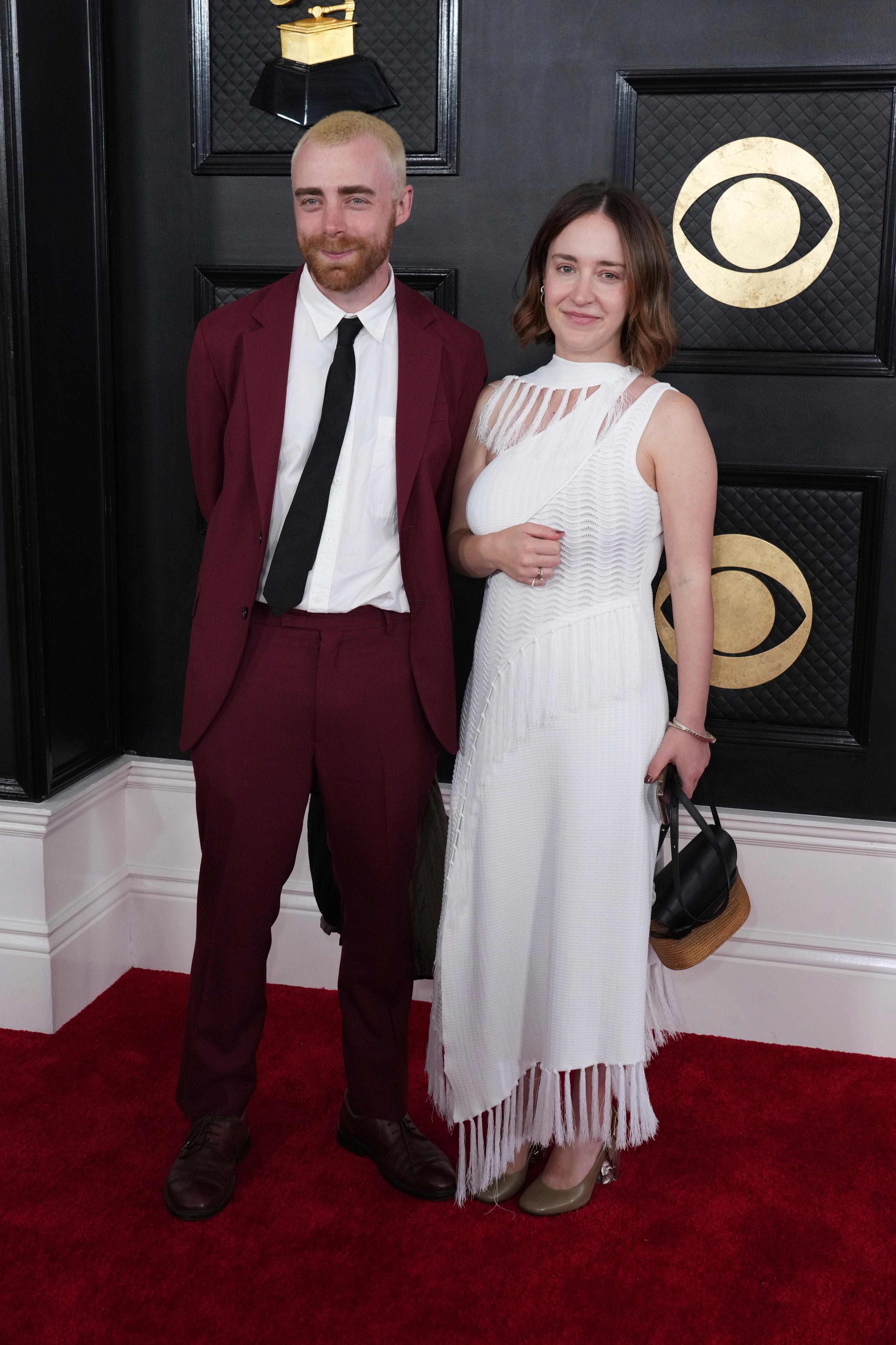 George Nicholas wearing a maroon suit and Ariel Bogle  in a white dress with fringed detailing. 