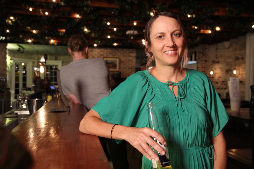 A woman with a beer in a pub looking at the camera.