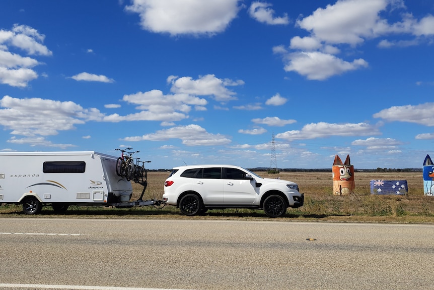 Caravan and SUV in front of "Bluey" hay bale art.