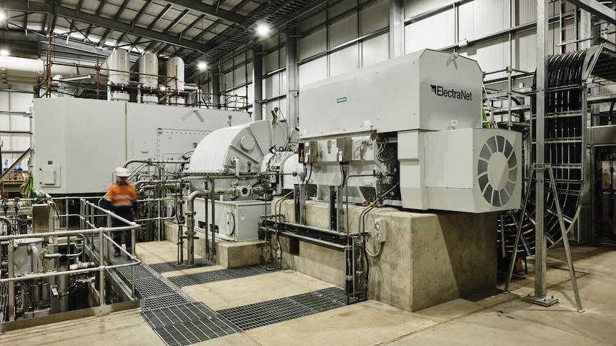 Industrial machine of steel and concrete in a huge shed with blurred worker to the side