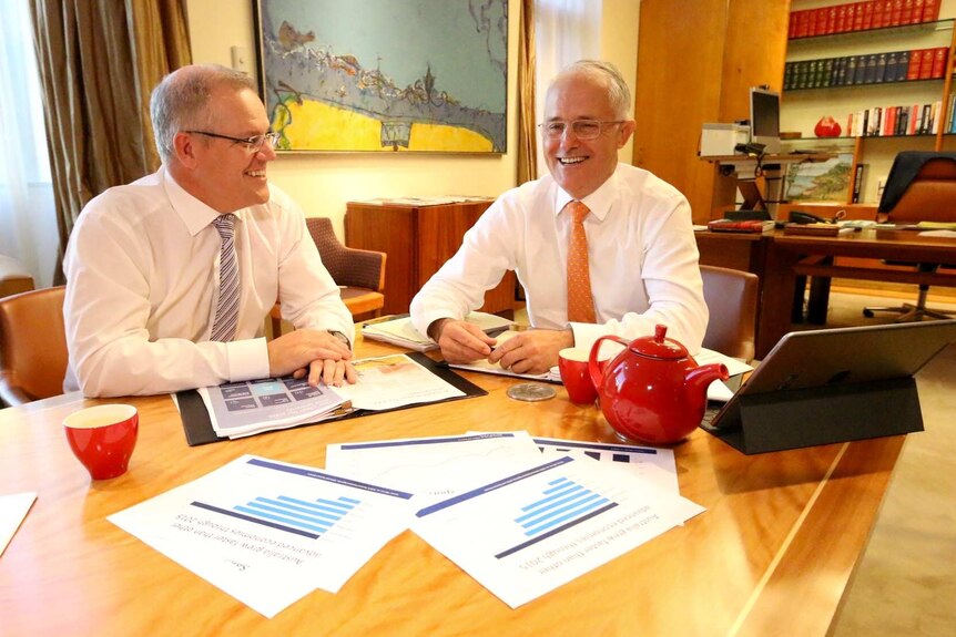 Scott Morrison and Malcolm Turnbull smile as they sit at a table in Mr Turnbull's office.