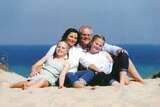 Prime Minister Scott Morrison, Jenny Morrison, and the couple's children Abbey and Lily sitting on the sand at a beach.