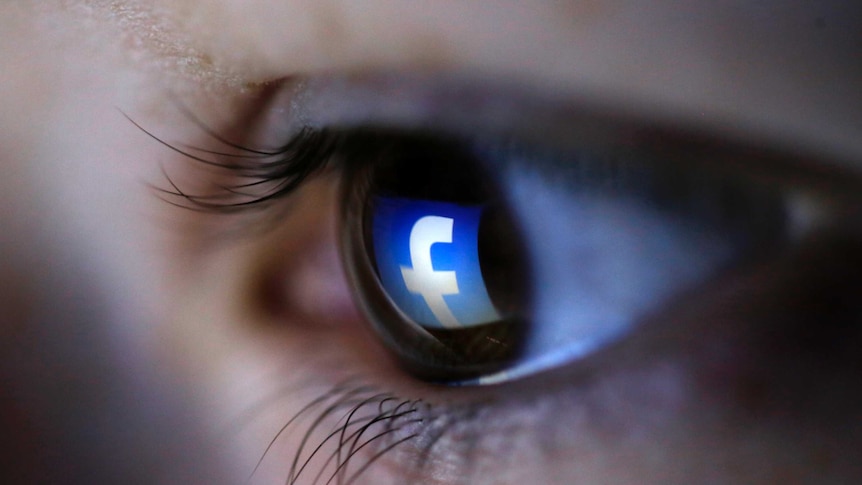 A Facebook logo is reflected in a person's eye